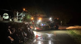 Saubermacher-Fahrzeug im nächtlichen Einsatz bei einer Überschwemmung, um Wasser und Schlamm nach einem Hochwasser zu entsorgen.