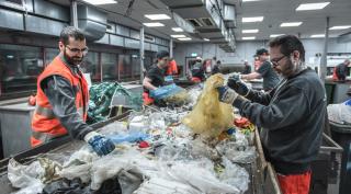 Saubermacher Mitarbeiter sortieren Kunststoffabfälle händisch am Fließband